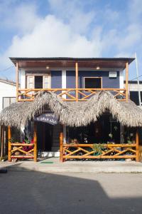 un edificio con techo de paja y porche en Hostel El Gran Azul Olon, en Olón