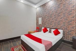 una camera da letto con un muro di mattoni e un letto con cuscini rossi di OYO Flagship Hotel New Pacifica Grand Near Phoenix United Lucknow a Charbagh
