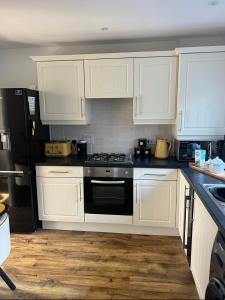 a kitchen with white cabinets and a black stove at Captains Quarters in Charlestown +20 photos