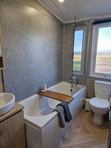 a bathroom with a tub and a toilet and a sink at Eden Lodge StAndrews, peace and tranquility. in Strathkinness
