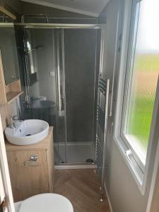 uma casa de banho com um chuveiro, um WC e um lavatório. em Eden Lodge StAndrews, peace and tranquility. em Strathkinness