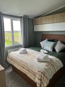 Strathkinness的住宿－Eden Lodge StAndrews, peace and tranquility.，一间卧室配有一张大床和两条毛巾
