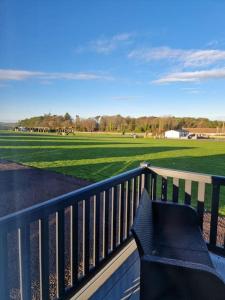 a bench on a balcony with a view of a field at Eden Lodge StAndrews, peace and tranquility. in Strathkinness