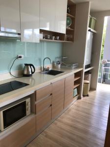 a kitchen with a sink and a microwave at Le Grand Bleu in Koh Samui 