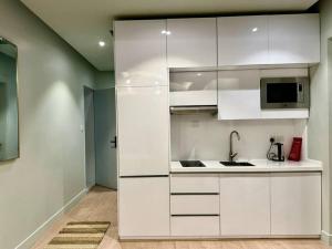 una cucina con armadietti bianchi e forno a microonde di Aurora Residence - شقة أورورا a Riyad