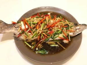 un plato de comida con un pescado con verduras. en จอมเมือง Motel, en Nan
