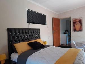a bedroom with a large bed with a black headboard at A humble abode that is cozy in Centurion