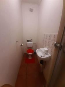 a bathroom with a red toilet and a sink at A humble abode that is cozy in Centurion