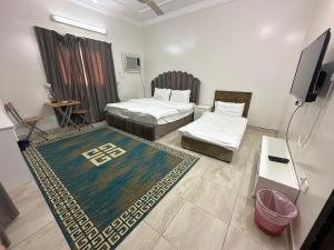 a room with two beds and a flat screen tv at Al-Olaya Apartment in Umm Lujj