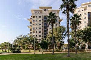 ein großes Gebäude mit Palmen in einem Park in der Unterkunft Jacuzzi Penthouse with wide Sea View in Natanya in Netanya
