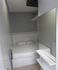 Piccola camera bianca con letto e specchio di Pousada Do Futuro a Fortaleza