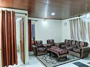 a living room with two chairs and a couch at Brindavan cottage in Madikeri