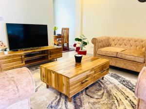 a living room with a television and a wooden coffee table at Oaklands Apartments in Morogoro