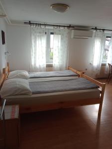 a large bed in a room with two windows at Sobe Černilogar in Tolmin
