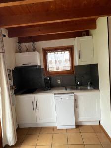 a kitchen with white cabinets and a sink and a window at Chalet des 2 lacs in Xonrupt-Longemer