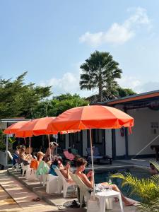 班拉克海灘的住宿－蘇梅島背包客旅館，一群人坐在草坪椅上,在伞下