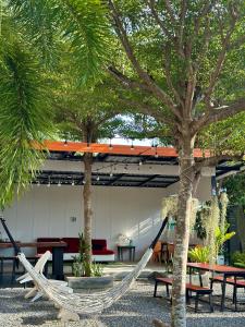 a hammock in a courtyard with tables and trees at Samui Backpacker Hotel in Bang Rak Beach