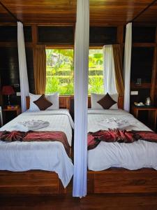 2 Betten in einem Schlafzimmer mit Fenster in der Unterkunft Villa Sande in Munduk