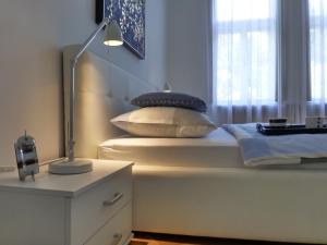 1 dormitorio con 1 cama con lámpara y almohadas en Konzul, en Osijek