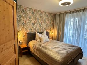 1 dormitorio con 1 cama y papel pintado con motivos florales en Brauner Bär, en Altenberg