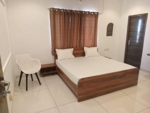 a bedroom with a bed and a chair in it at Vaatsaly Rooms in Indore