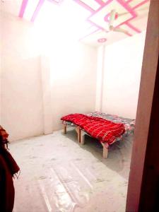 a room with a bed with a red blanket on it at Kumkum paying guest house in Ayodhya