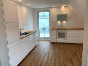 a kitchen with white cabinets and a wooden floor at Licht+Luft, Wohnen auf Zeit in Bad Nauheim