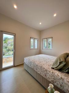 a bedroom with a bed and two windows at Haroupia Hillside Villa in Kalymnos