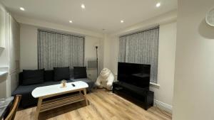 a living room with a couch and a flat screen tv at Modern Flat 5 Min From Wembley Stadium 30 Min From London in London