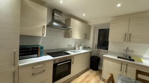 a kitchen with wooden cabinets and a stove top oven at Modern Flat 5 Min From Wembley Stadium 30 Min From London in London