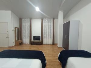 a bedroom with two beds and a flat screen tv at Edelweiss in Kohīma