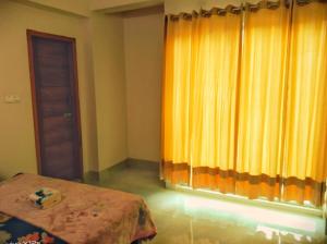 1 dormitorio con cama y cortina amarilla en Hasnahena 1/F,Dhaka Gurdren City,Adabar,Mohammadpur, en Dhaka