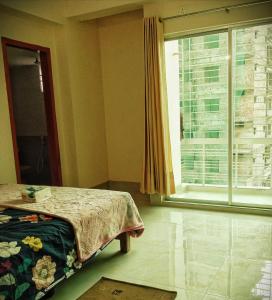 a bedroom with a bed and a large window at Hasnahena 1/F,Dhaka Gurdren City,Adabar,Mohammadpur in Dhaka