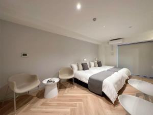 a bedroom with a large bed and two tables and chairs at bHOTEL Rijodori - Stylish Studio Apartment in Vibrant Hiroshima in Hiroshima