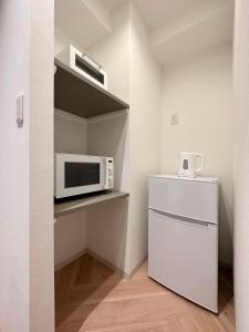 a small kitchen with a microwave and a refrigerator at bHOTEL Rijodori - Stylish Studio Apartment in Vibrant Hiroshima in Hiroshima