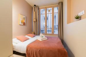 Schlafzimmer mit einem Bett und einem großen Fenster in der Unterkunft Charmant appartement moderne haut marais - 4P in Paris
