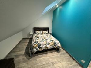 1 dormitorio con cama y pared azul en L’ÉCURIE, en Gigny