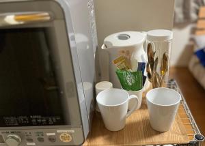 a group of cups sitting on a table next to a laptop at Guest room Kurume in Miimachi