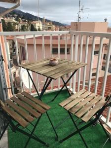 a wooden table and two chairs on a balcony at Lumineux studio sous les toits de Menton in Menton