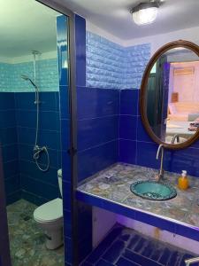 Baño azul con lavabo y espejo en Maison Les Grôttes, en Aït Ben Haddou