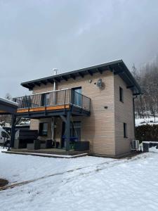 a house with a deck on the side of it in the snow at Casa Tara in Döbriach