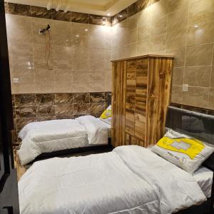 sypialnia z 2 łóżkami i ścianą w obiekcie استراحة وشاليه وقاعة السلطانه رجال w mieście Al-Salam