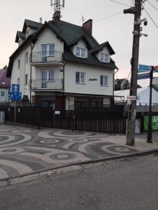 Una gran casa blanca con una acera de azulejos en la parte delantera en Pensjonat Melodia en Pobierowo