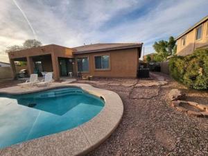 a house with a swimming pool in front of a house at Cozy Latitude home with pool in Goodyear