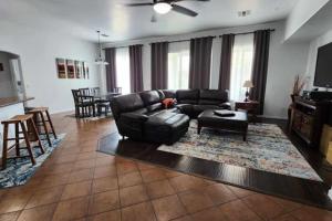 a living room with a black leather couch and a table at Cozy Latitude home with pool in Goodyear