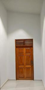 uma porta de madeira castanha num quarto branco em Archie Homes em Kadawata