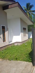 uma casa branca com um relvado verde em frente em Archie Homes em Kadawata