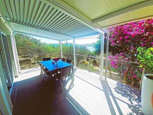 a screened in porch with a blue table and flowers at 1 Haus Linden Osljak in Island Osljak +3 photos