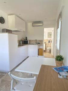 a kitchen with white cabinets and a table in it at Chez Nous - Studio in La Môle