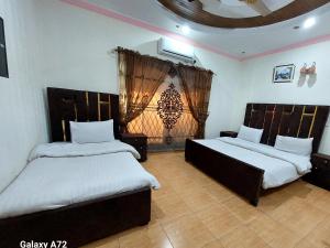 1 dormitorio con 2 camas y ventana en Hotel Eden Plus Lahore, en Lahore
